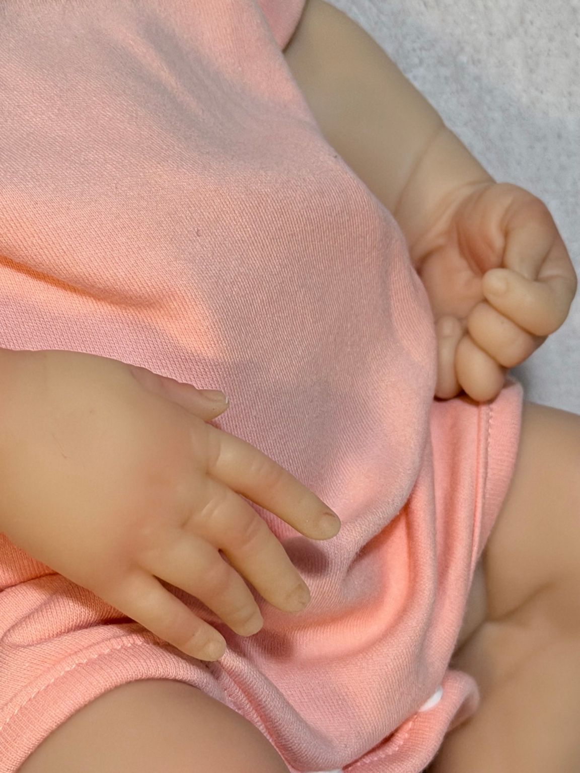 Reborn bebé completa con ropa rosa y pose natural sobre fondo blanco.