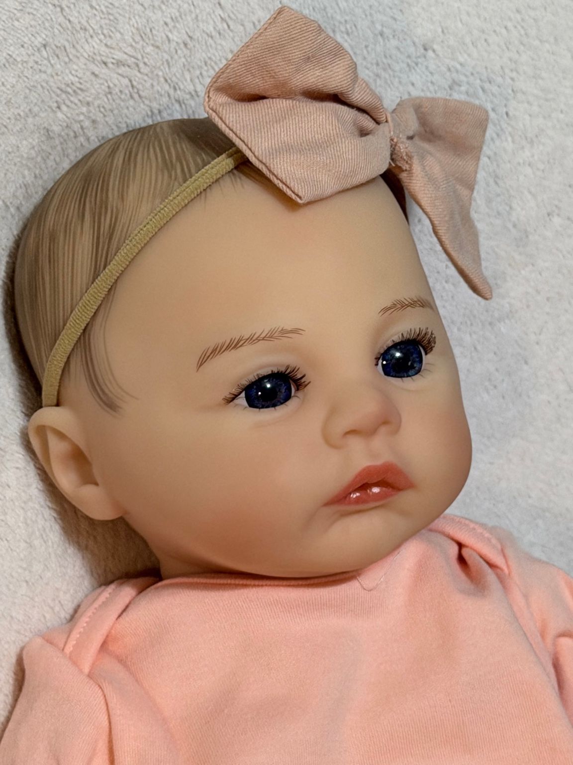 Muñeca reborn bebé con chupete rosa, fondo blanco y detalles realistas
