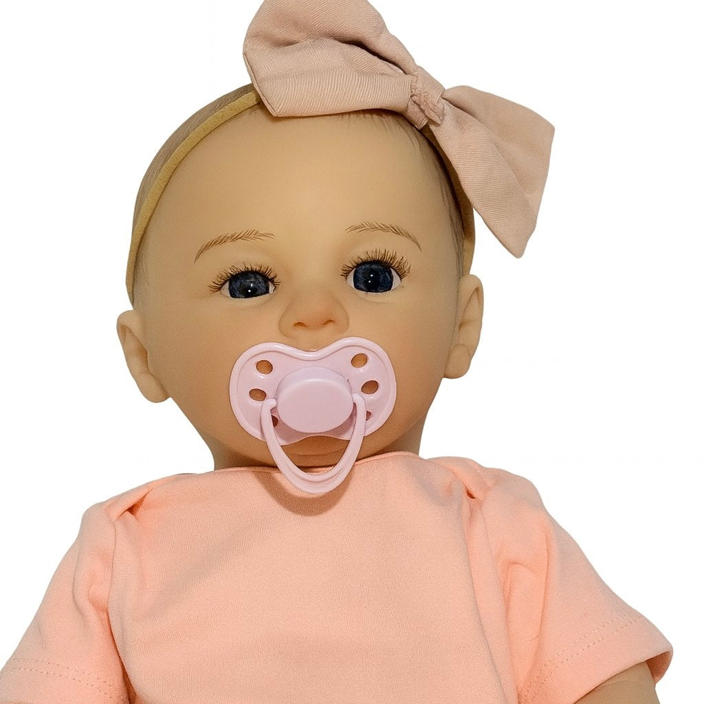 Muñeca reborn bebé con fondo blanco, traje rosa y chupete, fotografía estilo catálogo