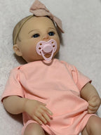 Reborn bebé realista con accesorios rosados y luz de estudio.